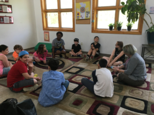 Group of young learners speak openly in a circle on the floor