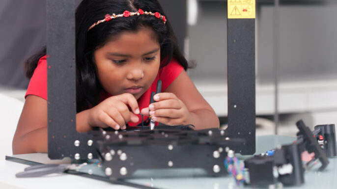 Young girl, 8 year old assembling a 3D printer kit for STEM summer camp