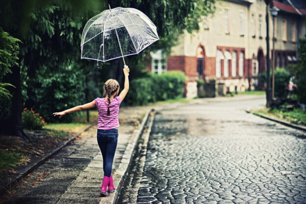 Little girl walking on a sidewalk in rain.