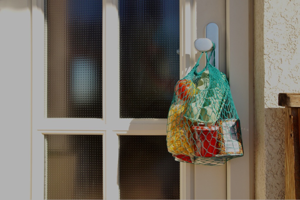 photo of a netted grocery bag holding food hung up on a doorknob