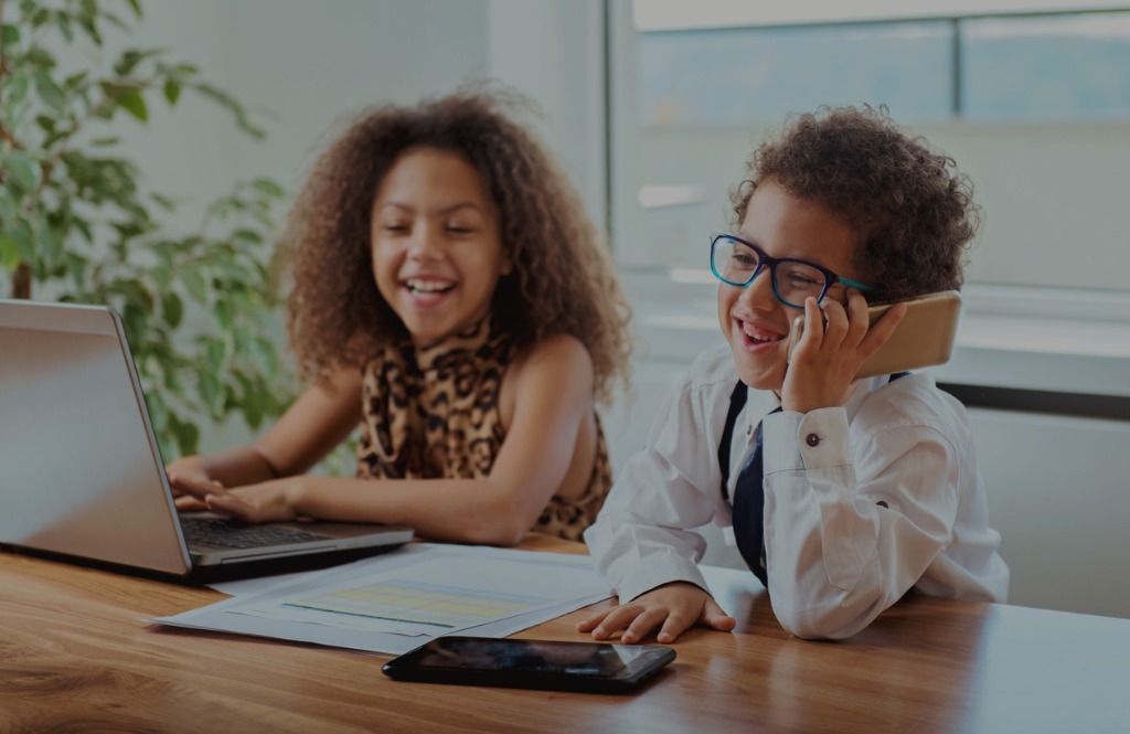 two young learners dressed in business outfits in front of a laptop