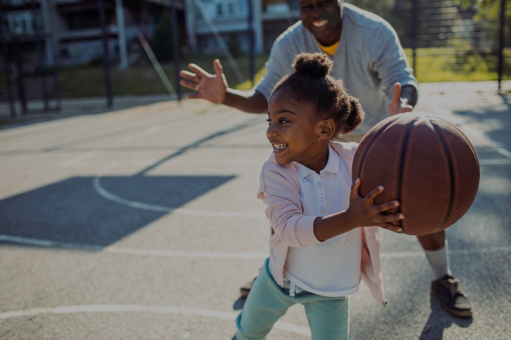 young learner playing basketball with an educator