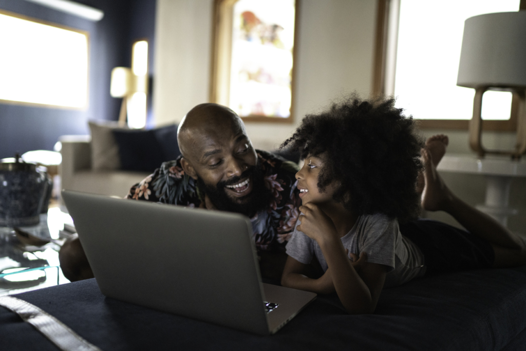 father wacthing movie on a laptop with his daughter