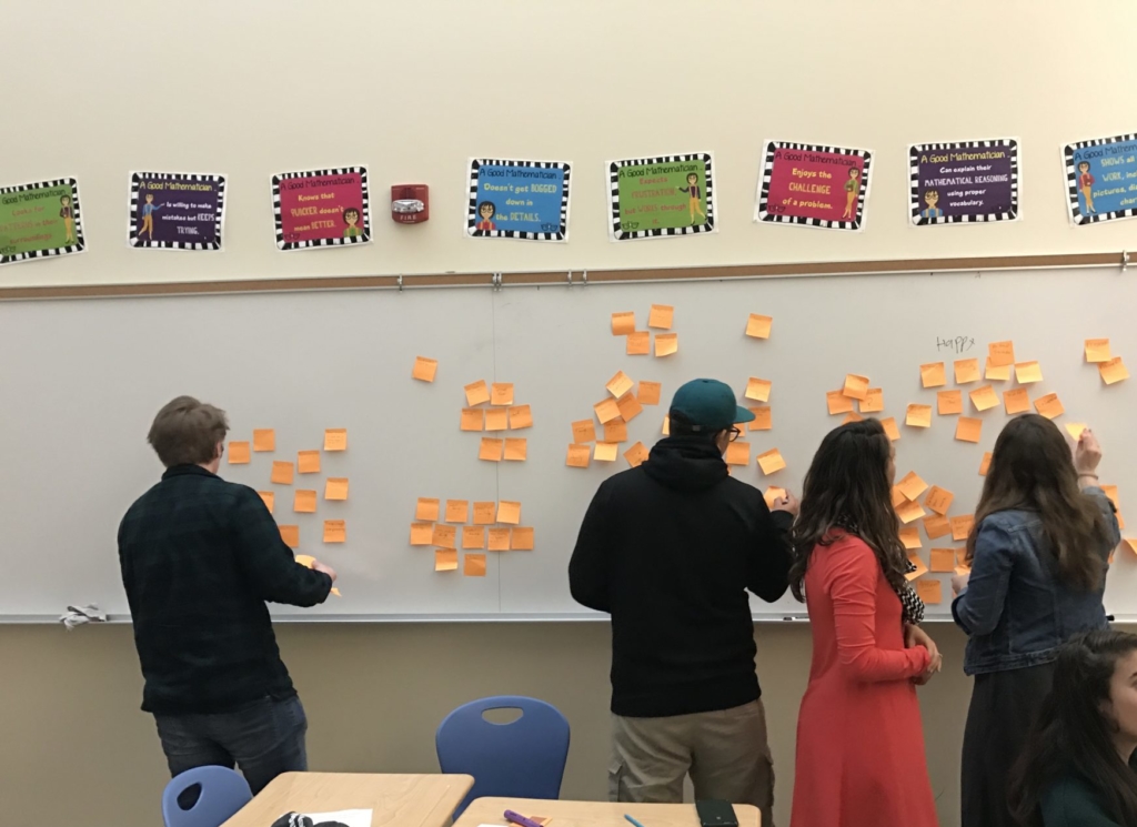 Reinvisioned group in front of a wall with post-it notes