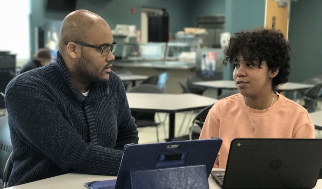 young learner and practitioner around a table in front of laptops