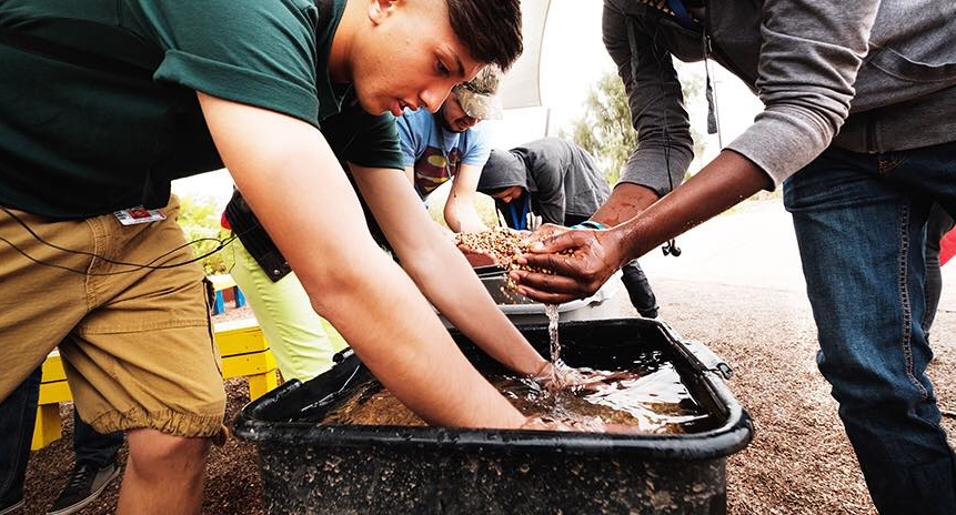 learners outside washing vegetables in a community school garden program