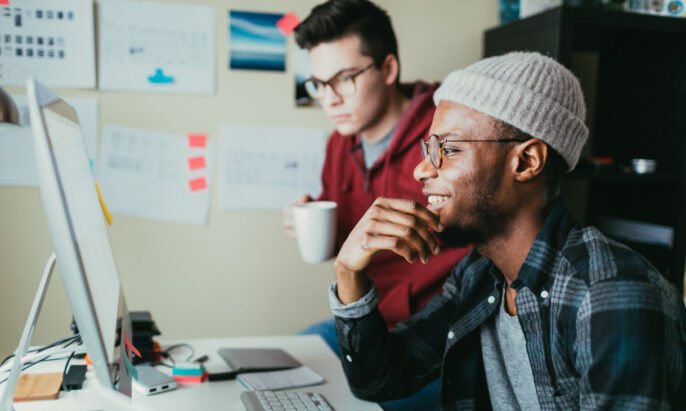 two young men in front of a desktop computer