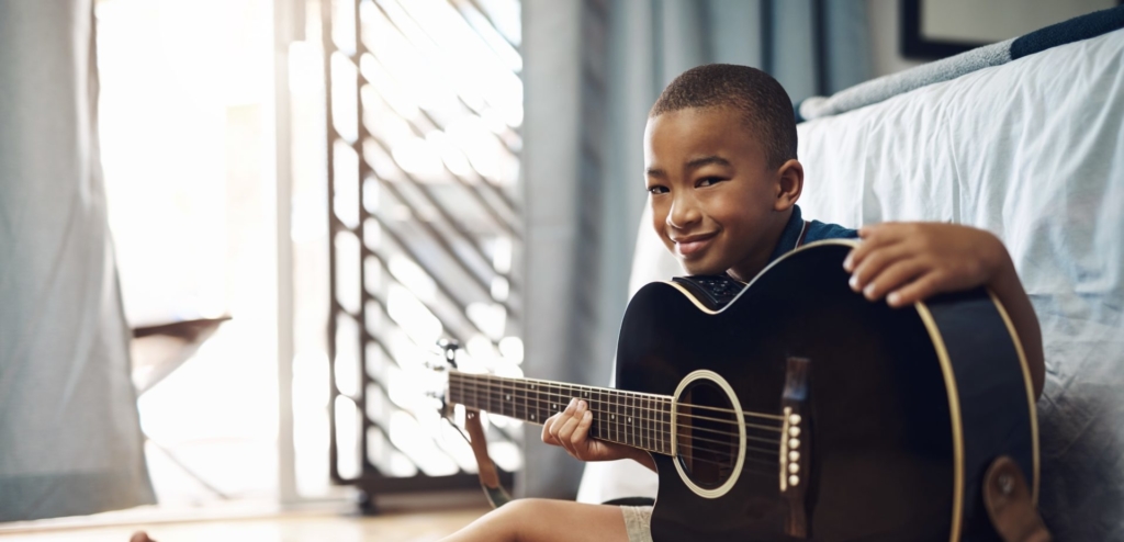 young learner holding a guitar