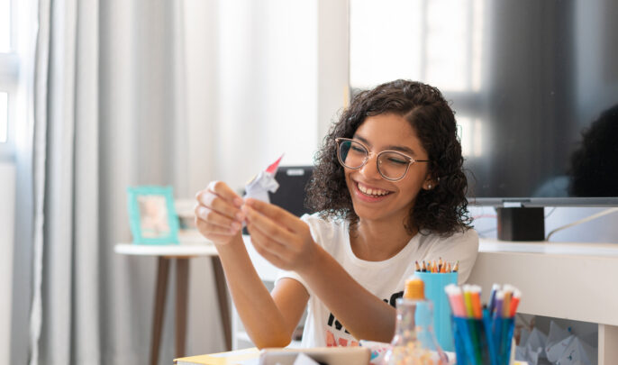 Teenager girl making an origami in quarantine during the world COVID-19 pandemic in 2020