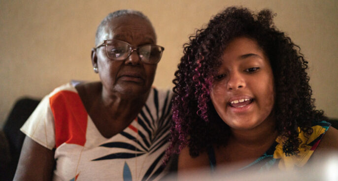 Grandmother and granddaughter having a video call on digital tablet at home