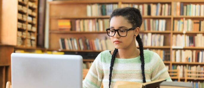 learner in front of a laptop in a library