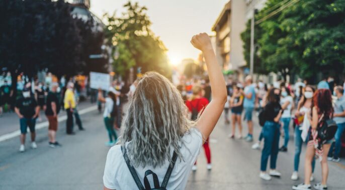 learner holding up her fist in front of a crowd