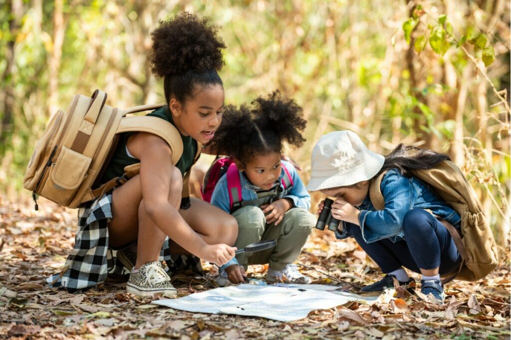 group of young learners looking at a map in the woods