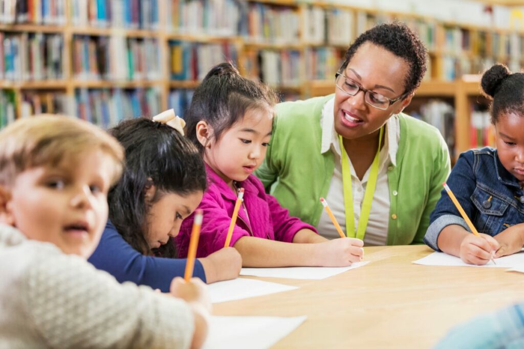 group of young learners with a practitioner at a table in the library