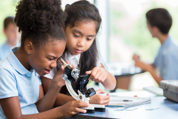 photo of two young learners looking through a microscope