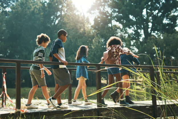 photo of learners walking across a wooden bridge outside