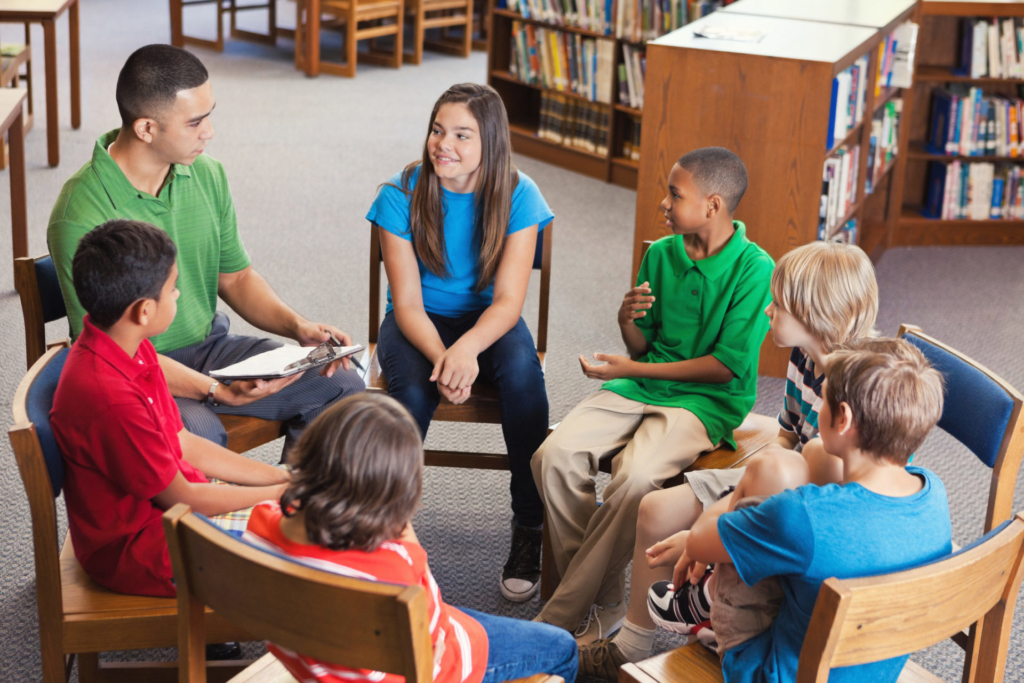 group of learners in a library sitting in a circle on chairs