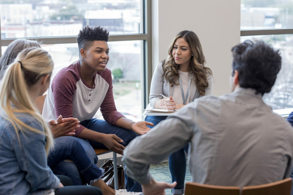 photo of learners sitting on chairs in a circle talking