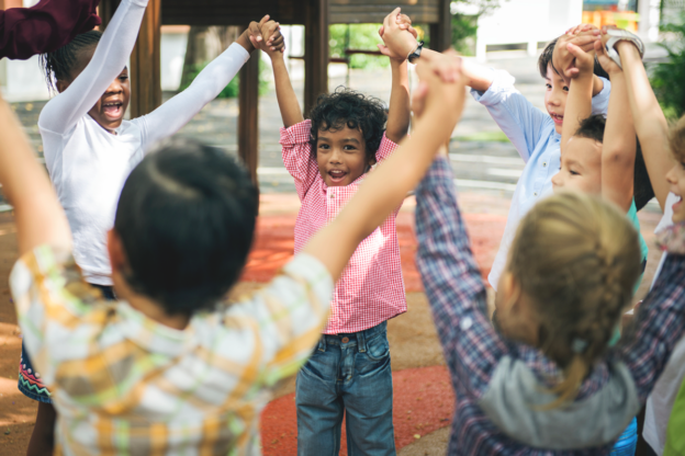 young learners in a circle holding hands