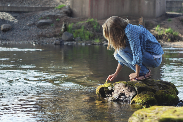 learner sitting on a rock near water