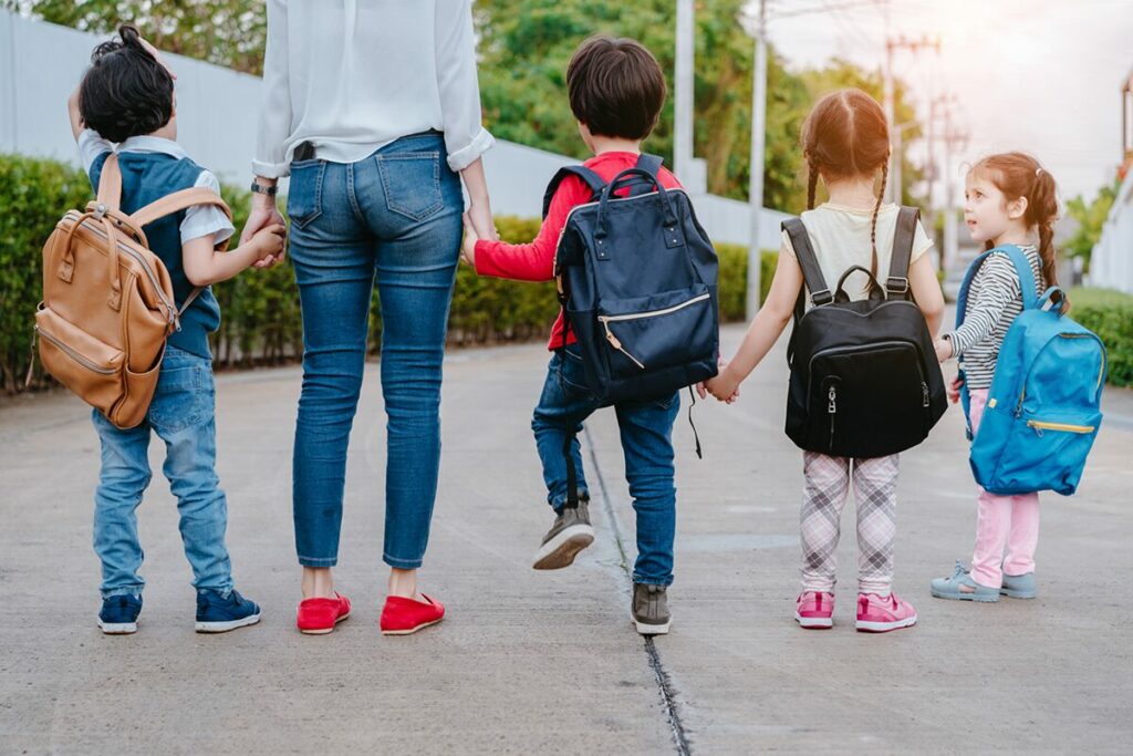 young learners holding hands wearing backpacks