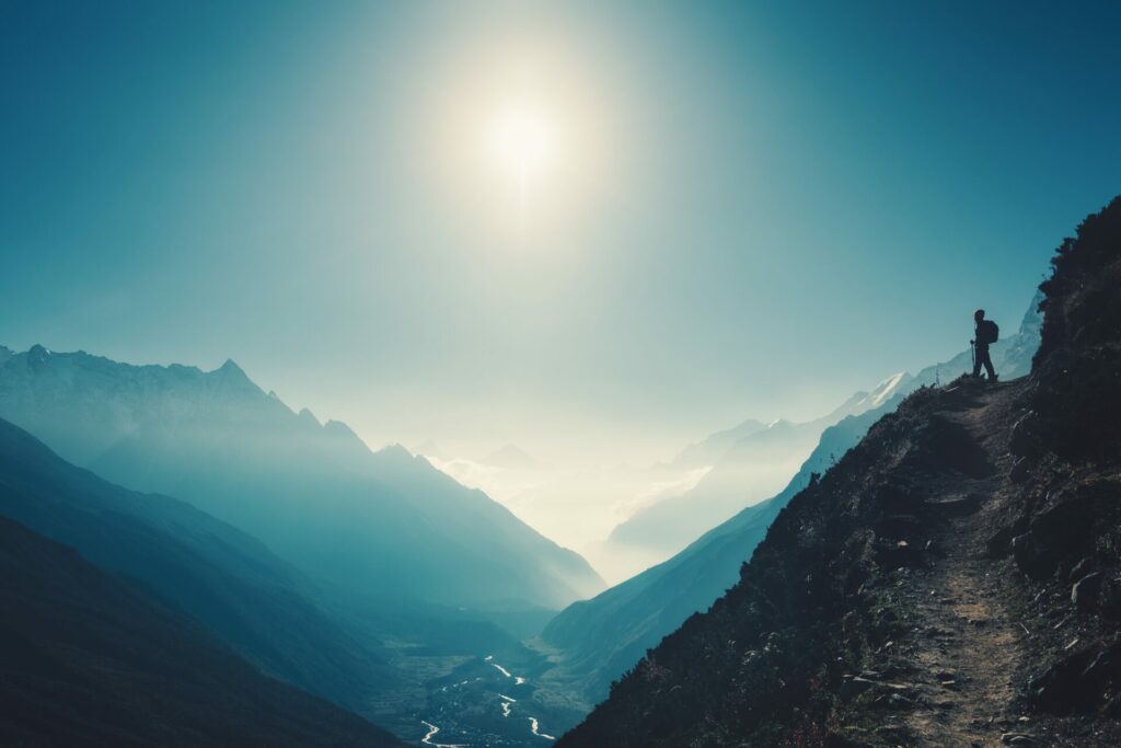 photo of a vast mountainous landscape with a a hiker on a trail