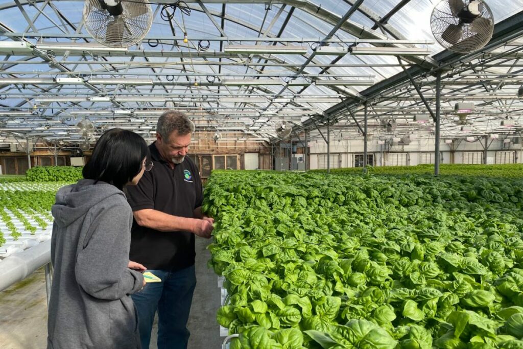 Kim McKellar with a U-32 learner inside a large greenhouse