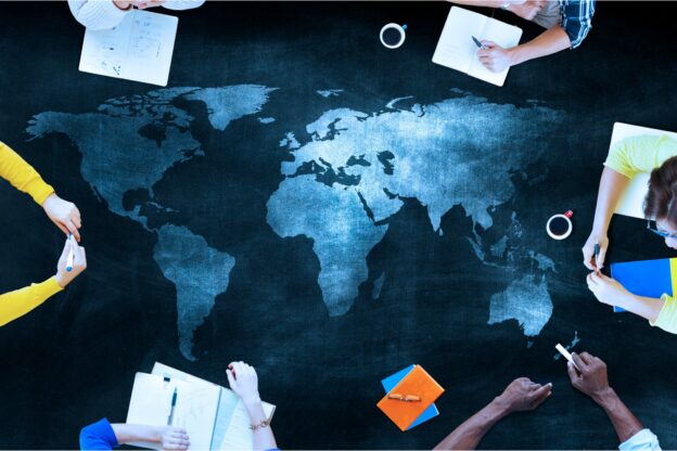 aerial photo of the table with the map of the world on and learners sitting around it