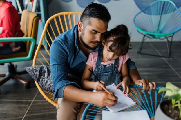 young learner with guardian drawing in a notebook together