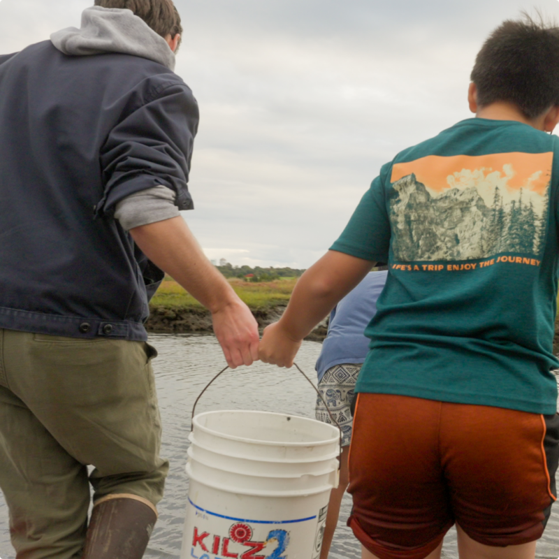 Fab Newport learners holding a bucket by the water