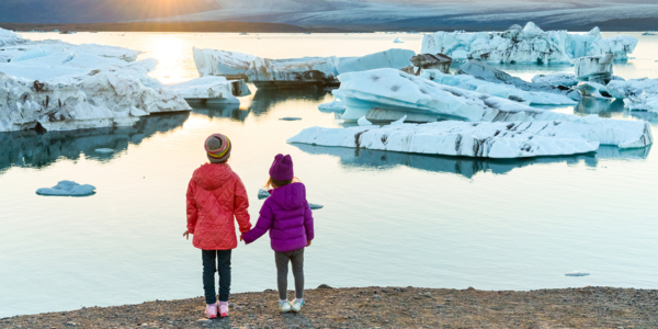 two learners holding hands looking out across a body of water