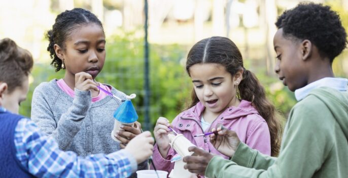 young learners painting wooden objects together