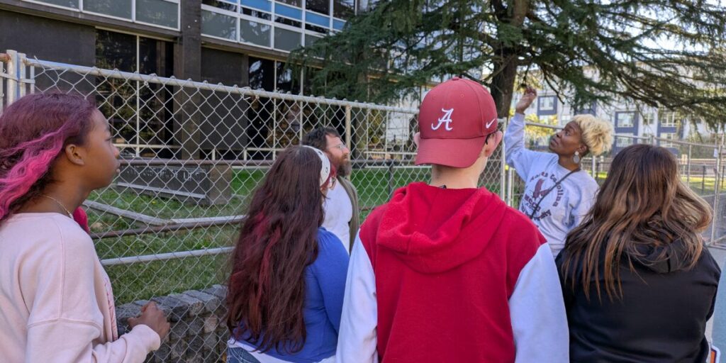 Young people outside of a building with a community member learning 